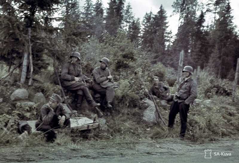 Historical reference photograph of Finnish soldiers resting in a forest, credited to SA-kuva.